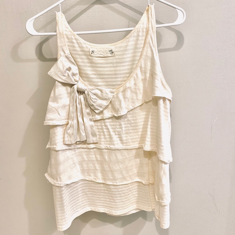 Sleeveless top with silk bow application in front.